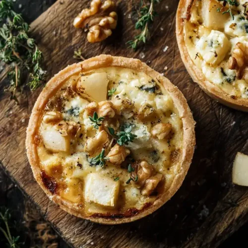 Mini-Quiche mit Birnen und Gorgonzola frisch gebacken auf Holzbrett